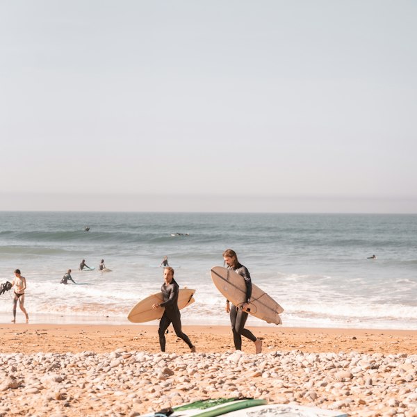Surfers carrying boards at sunset