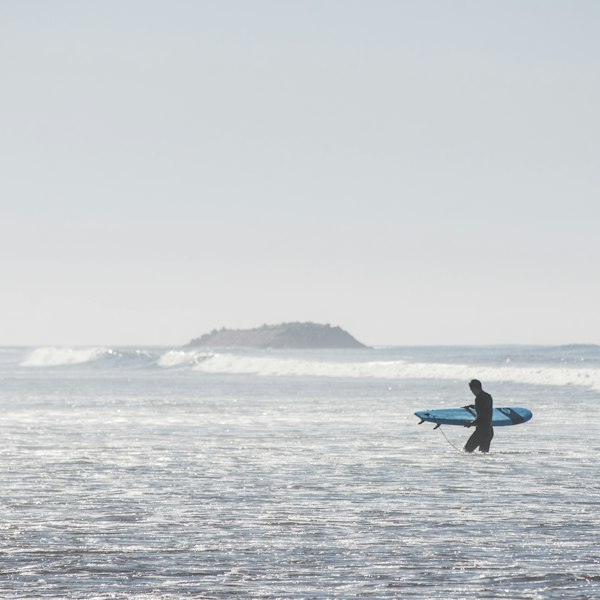 Surfer walking with blue board on beach